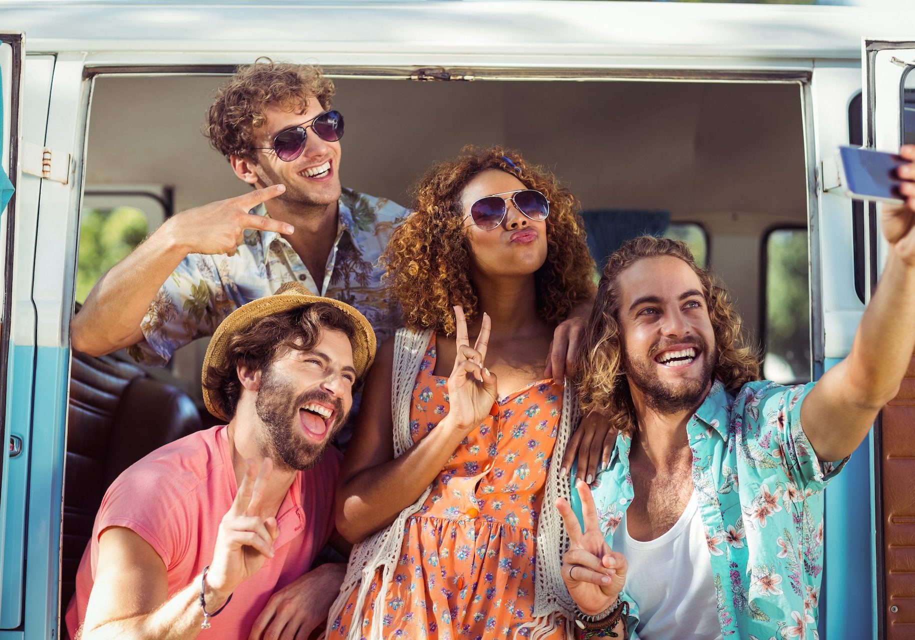 Group of happy friend taking a selfie in campervan at park